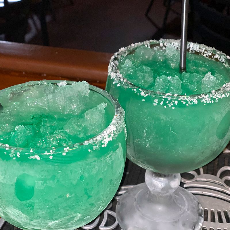 Two frozen green margaritas with salted rims