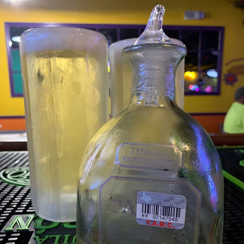 A frosted drink next to a bottle of Patrón tequila on the bar